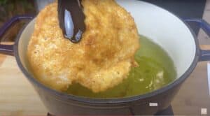 Crispy breaded schnitzel frying in a hot oil pan, golden brown and delicious.